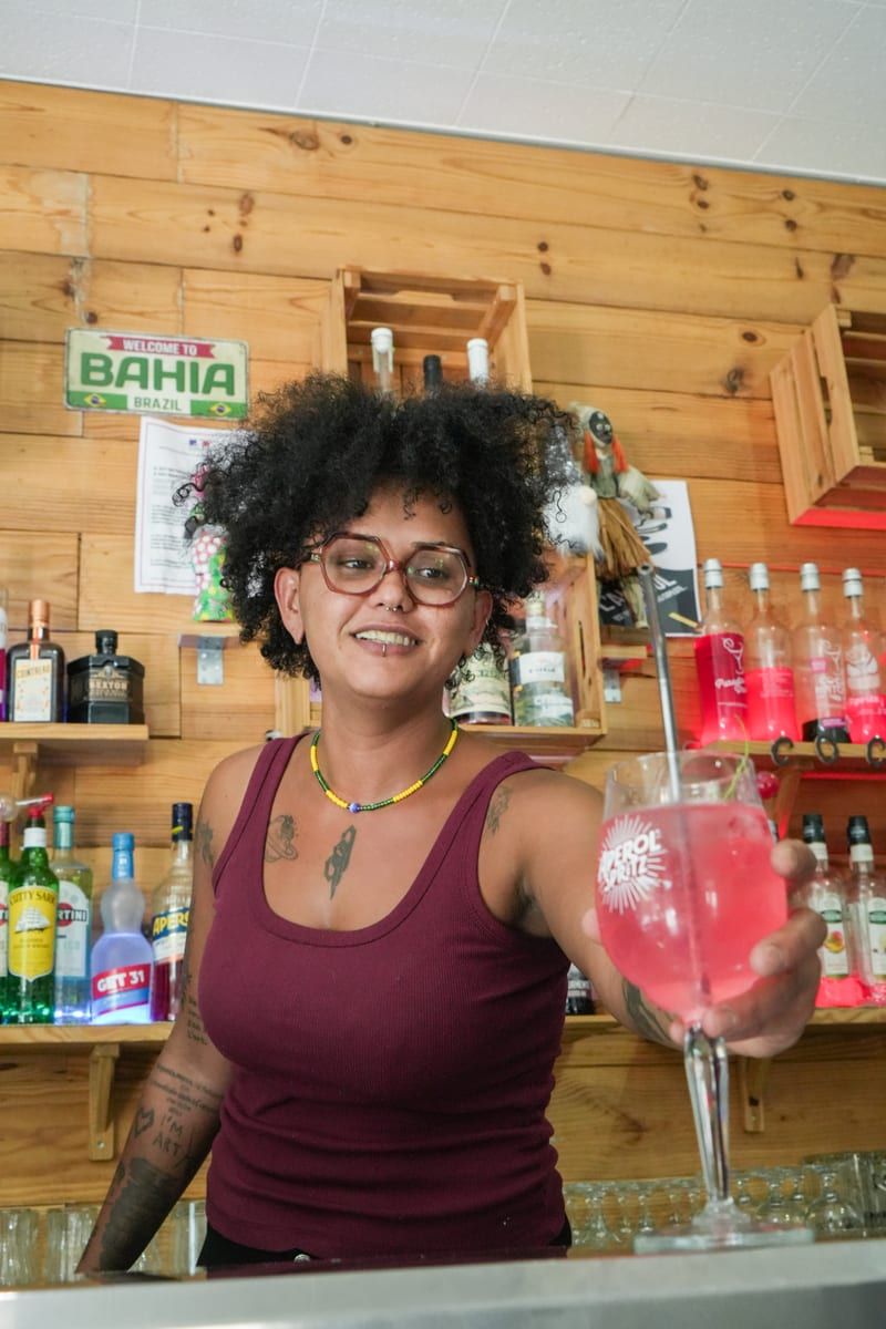 Amanda, souriante, un cocktail à la main derrière le bar