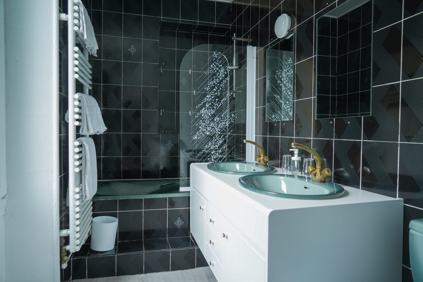 Salle de bain de la chambre Double Deluxe, carrelage noir et robinetterie dorée